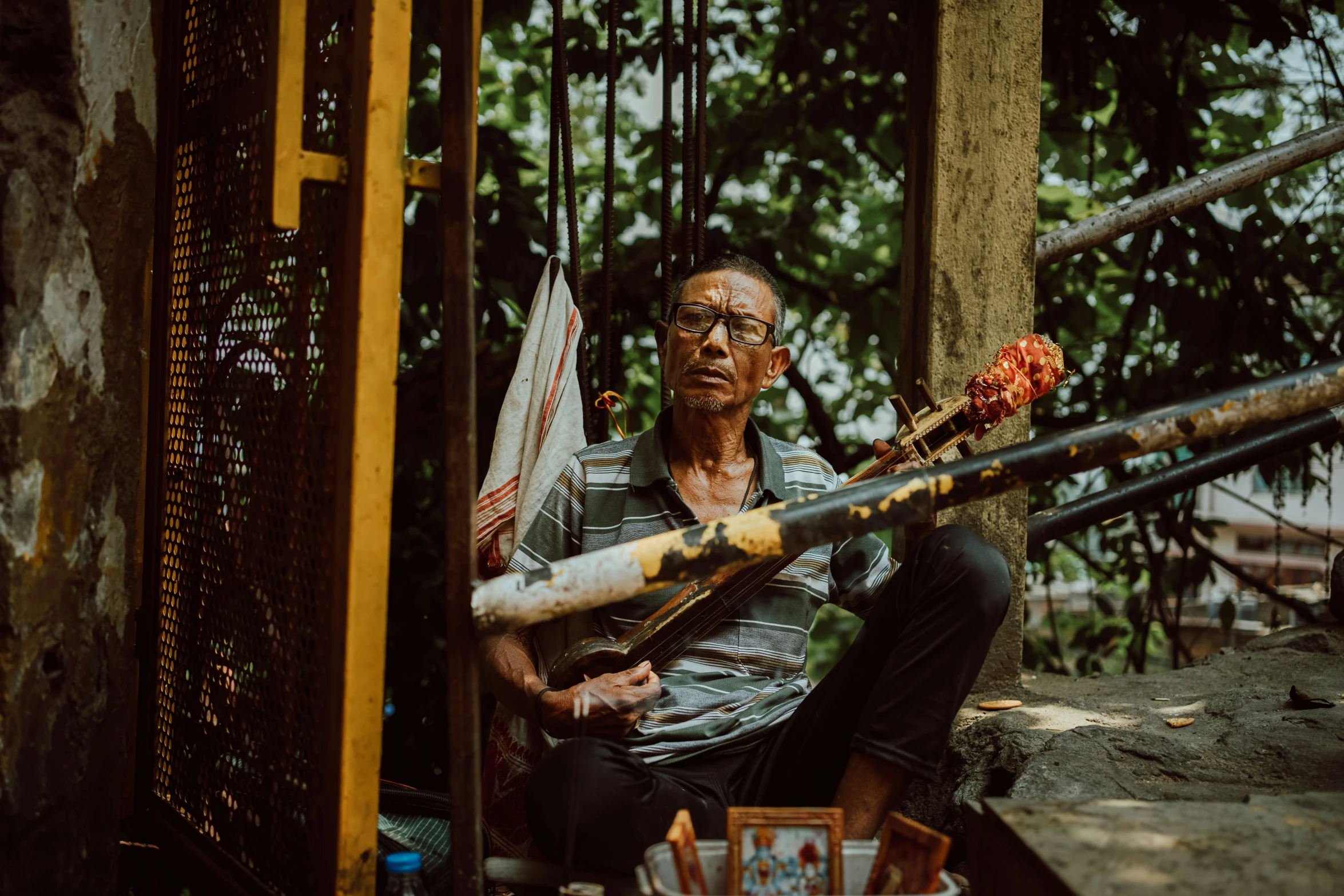 an old man with a stick on his neck is sitting near some bars