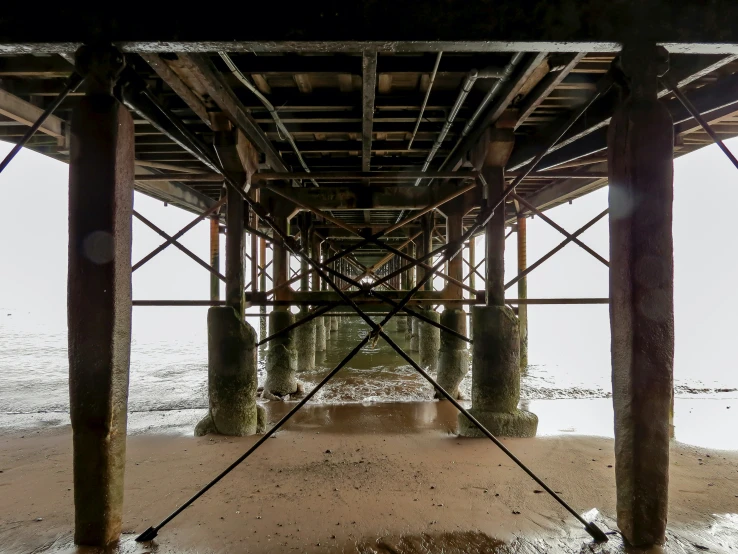 a wooden pier sitting under a metal bridge