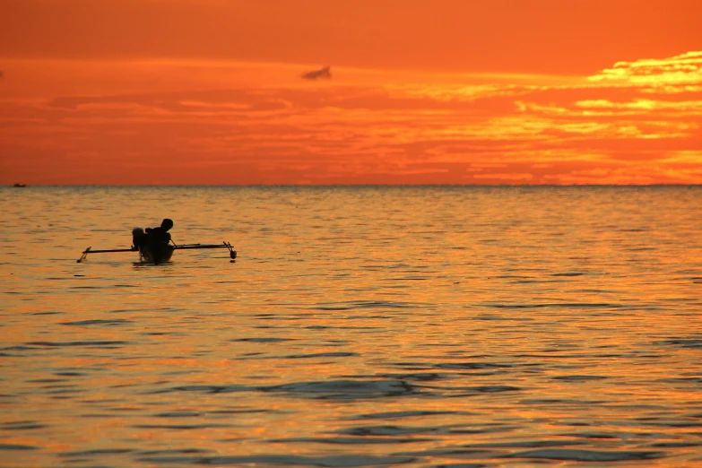 a person in a rowboat on the water at sunset