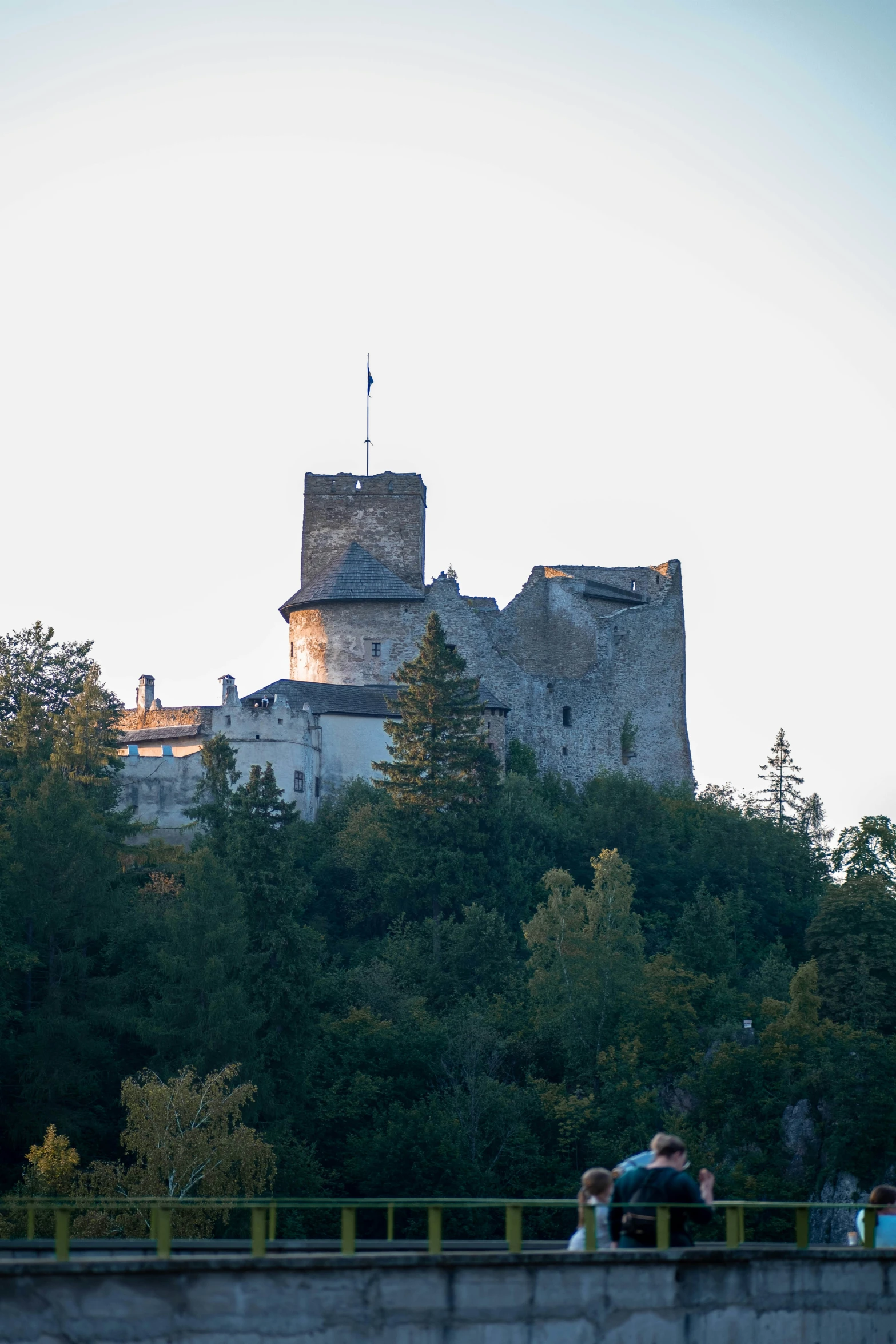 two people sitting on a bridge in front of a castle