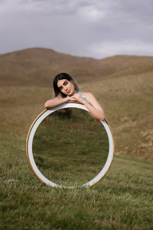 a woman sitting on top of a round object in the grass