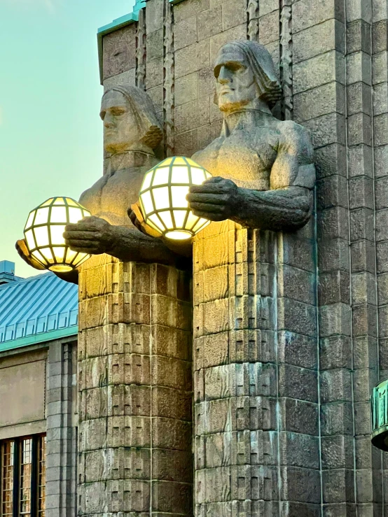 two large lamps and statues are lit up on a light post