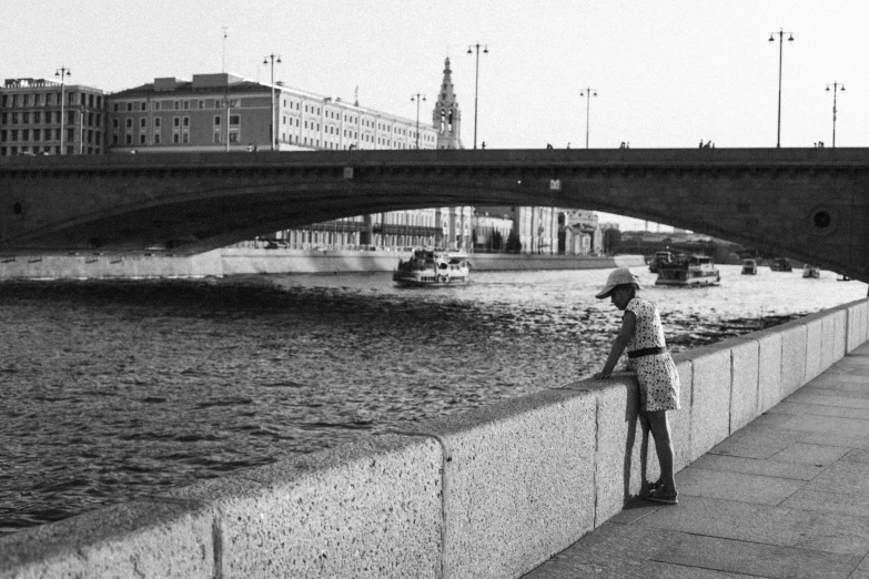 a woman standing by the water with an umbrella