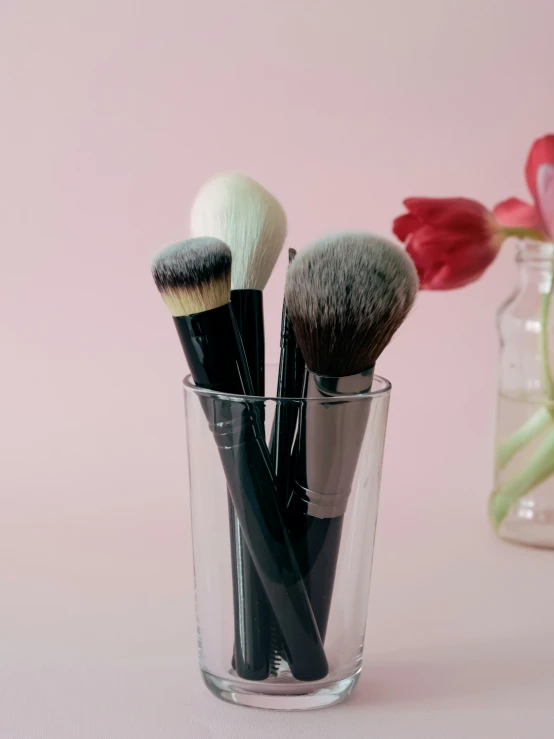 a close up of three brushes in a glass on a table