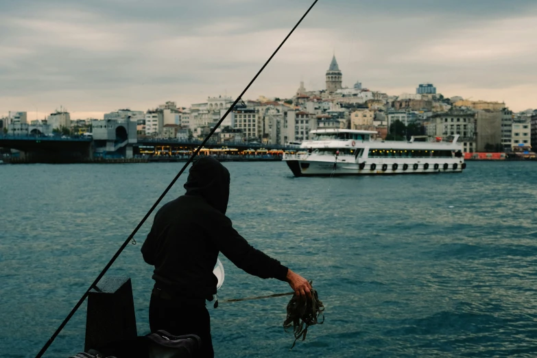 a person is fishing off the water by a ship