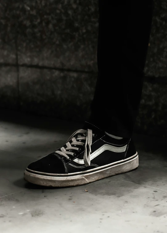 a person with black and white sneakers is standing on cement