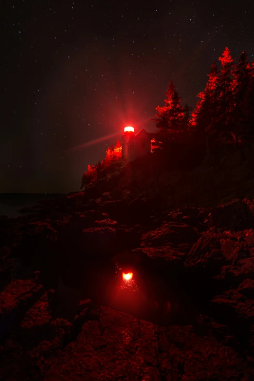 a red car parked on a rocky shoreline at night