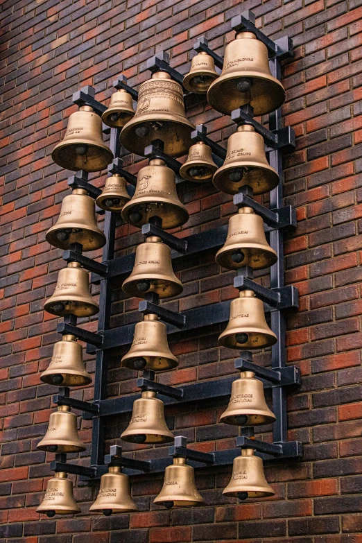 a group of bells hanging from the side of a brick building