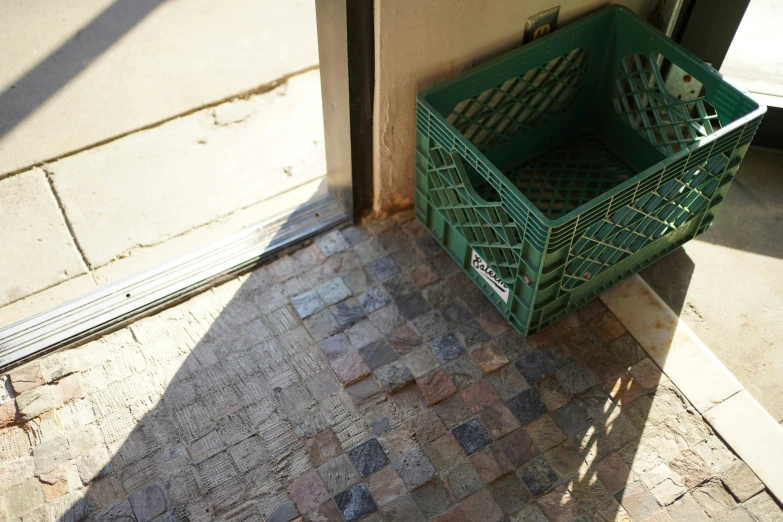 a green basket sitting next to an open door