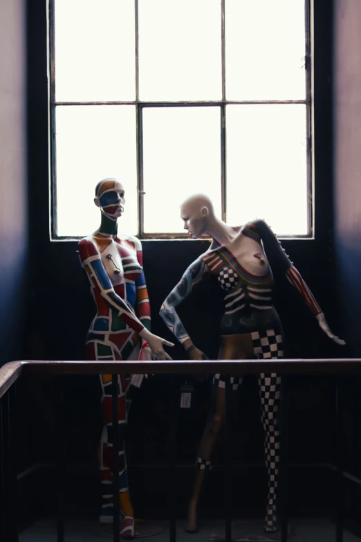 two mannequins in costumes standing near a window