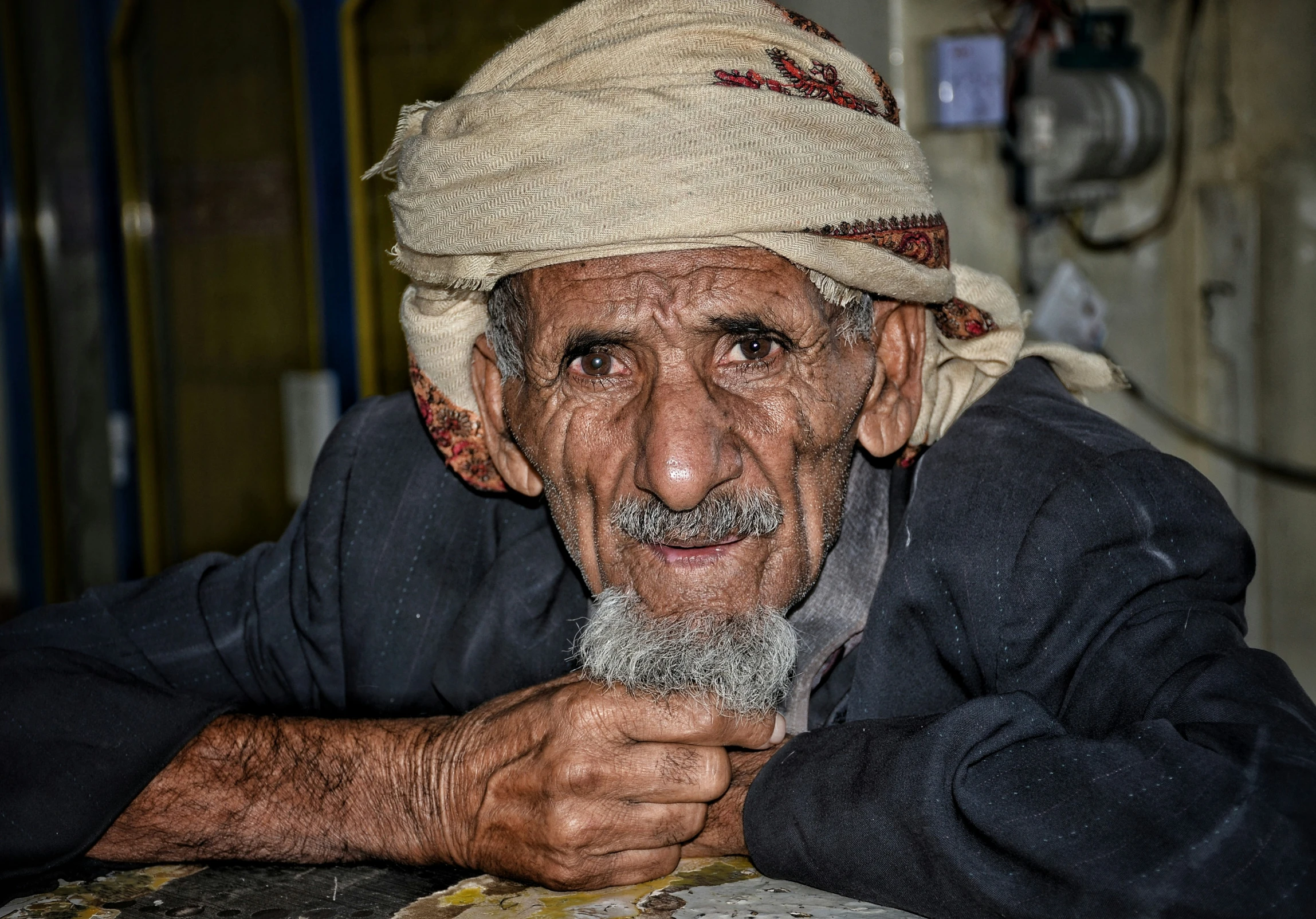 an elderly man in a hat looks at the camera