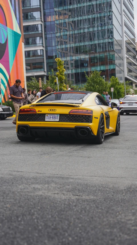 a yellow car parked in a parking lot in front of tall buildings