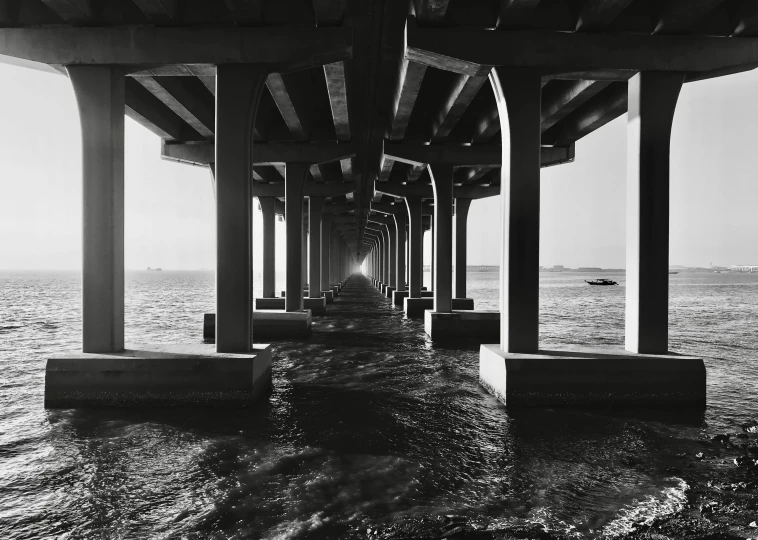 the ocean is under an open bridge by a plane