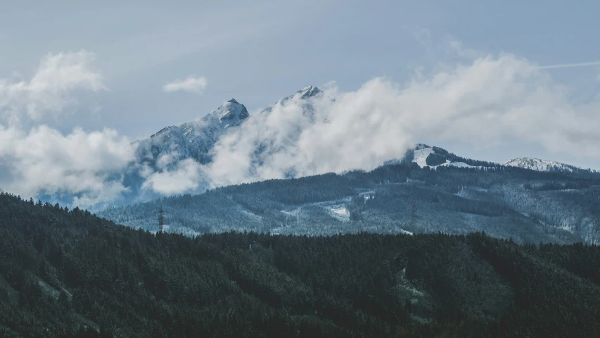 mountains are covered in clouds and some snow