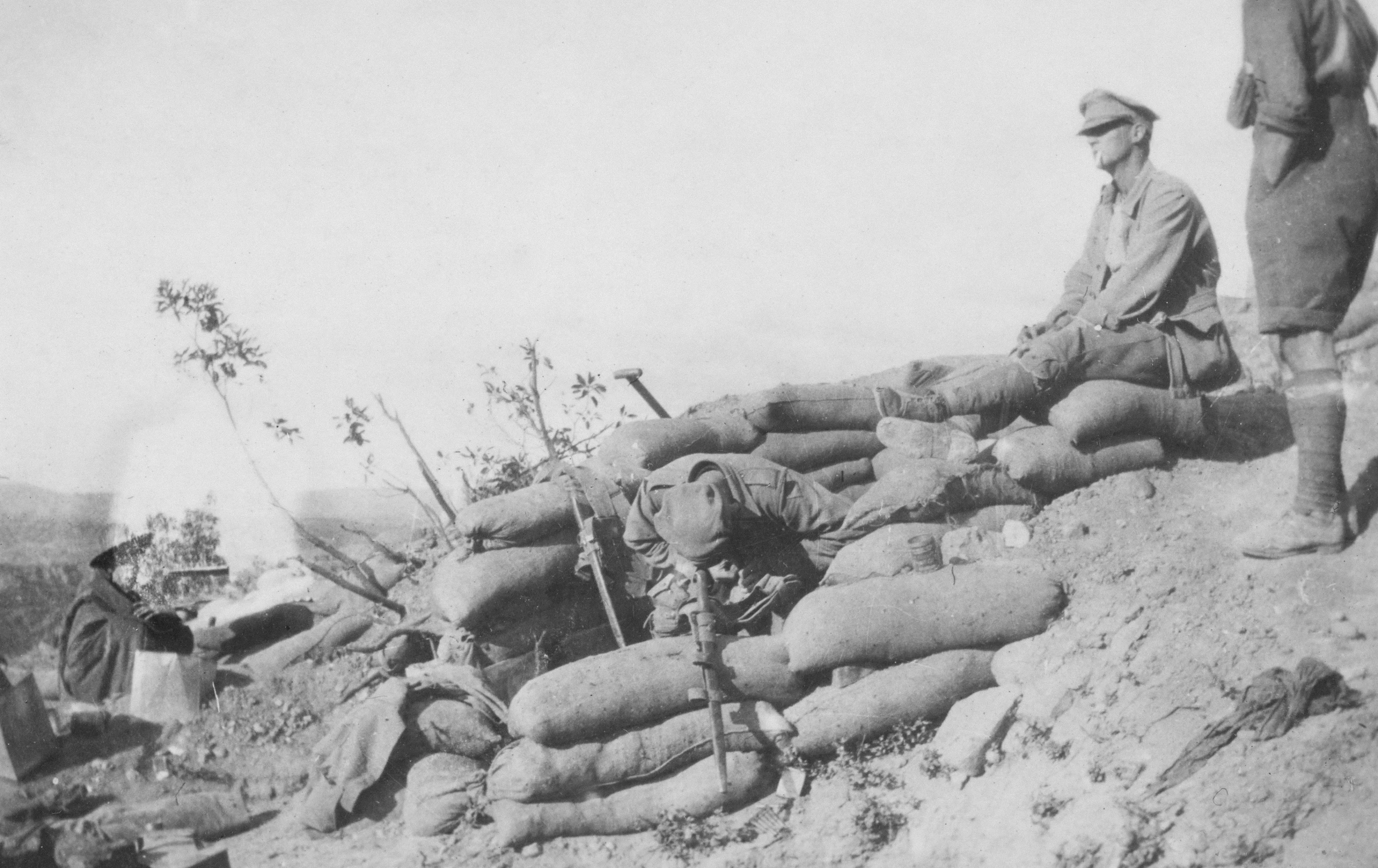 two soldiers looking on as some sand bags lay on them