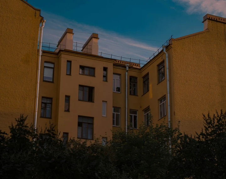 the side of a tall yellow building with barbed wire around it