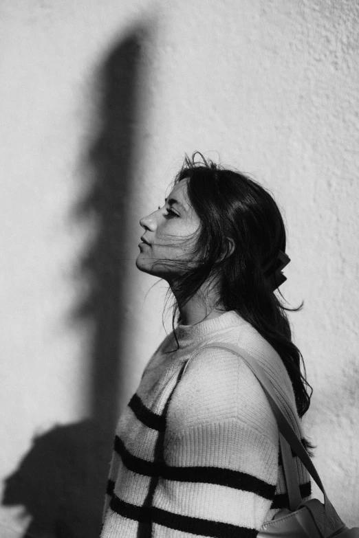 a black and white po of a woman with her shadow cast on the wall