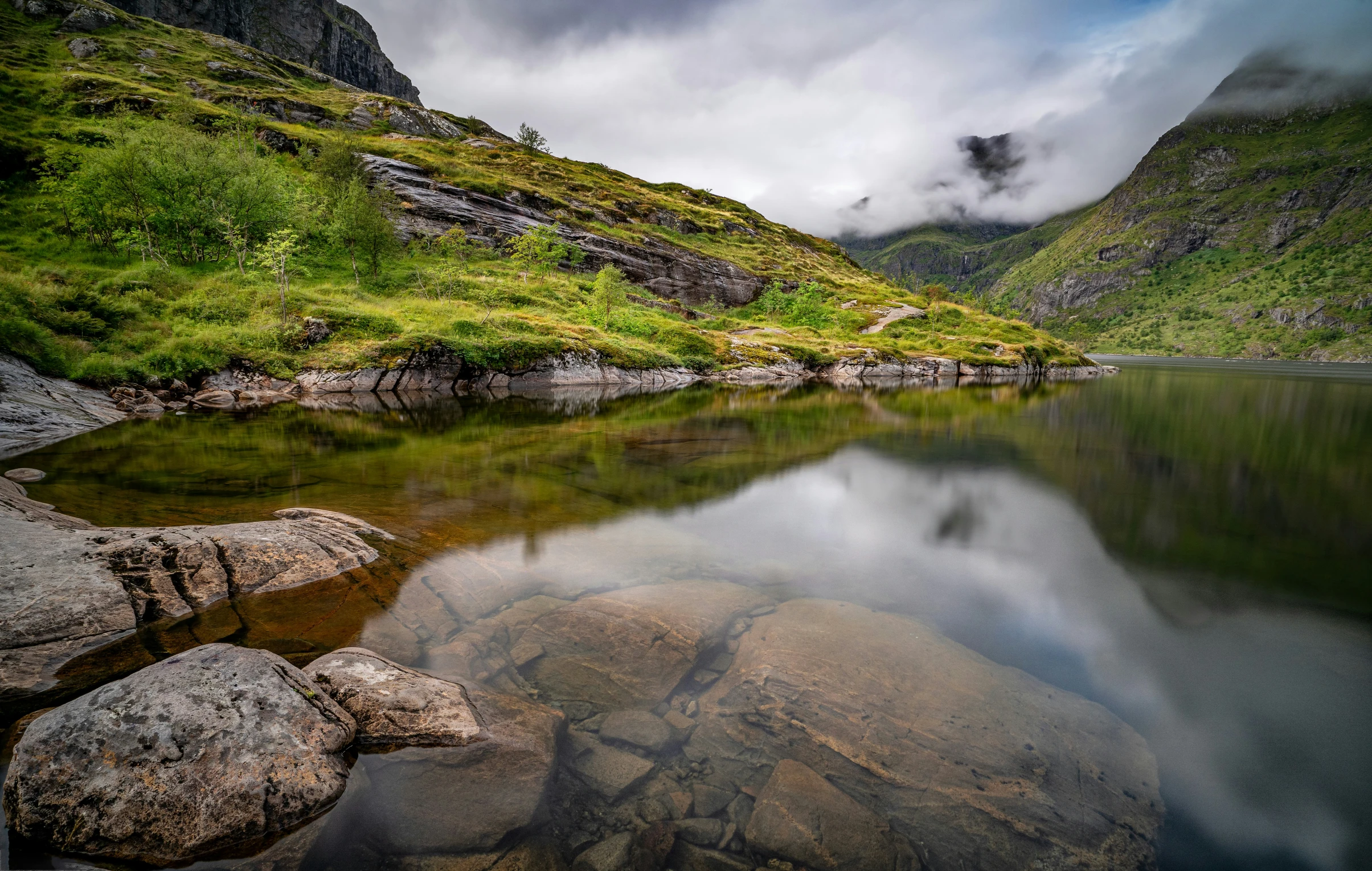 a large body of water surrounded by rocks and grass