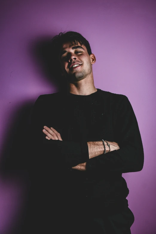 a man is posing in front of a purple wall