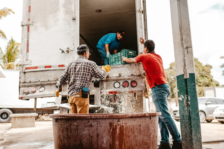 two men are unloading some type of trash into a truck