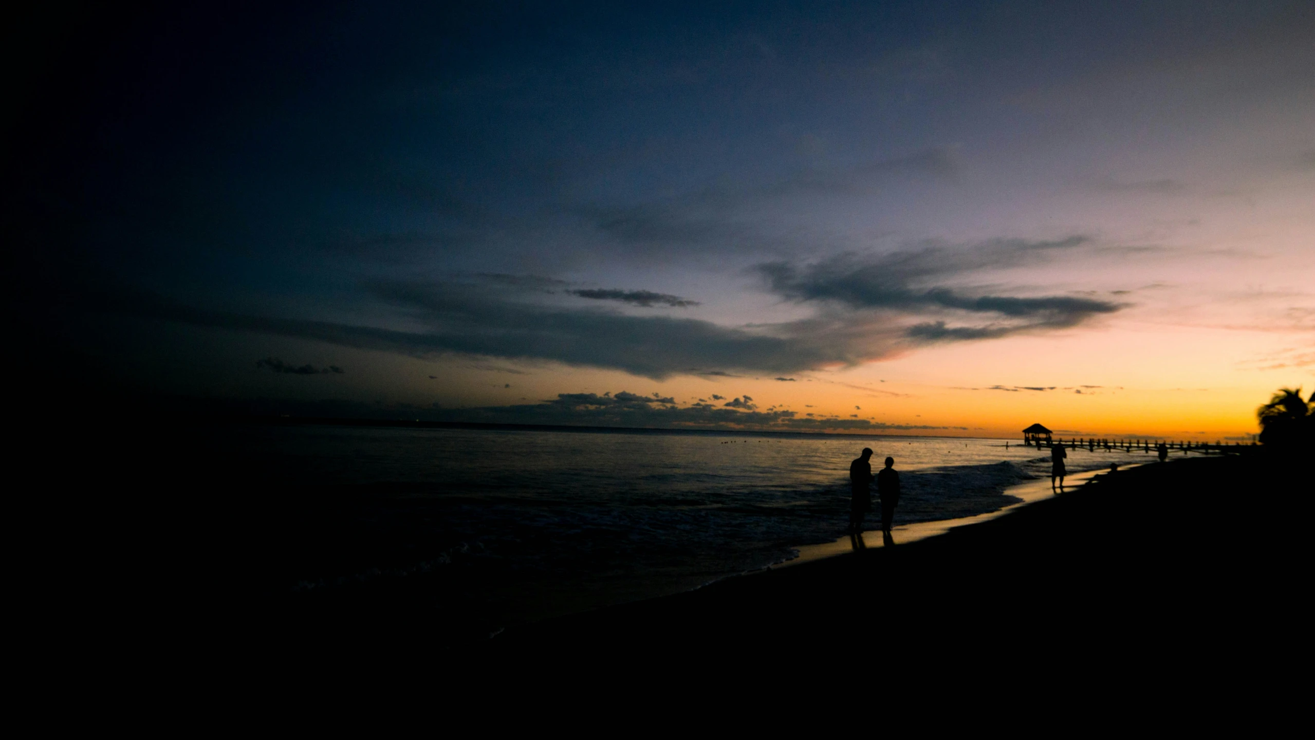 a dark, cloudy sunset with the sun setting in the distance