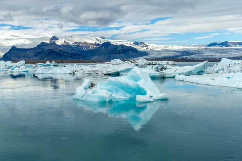 the mountains are behind the water and there is an iceberg