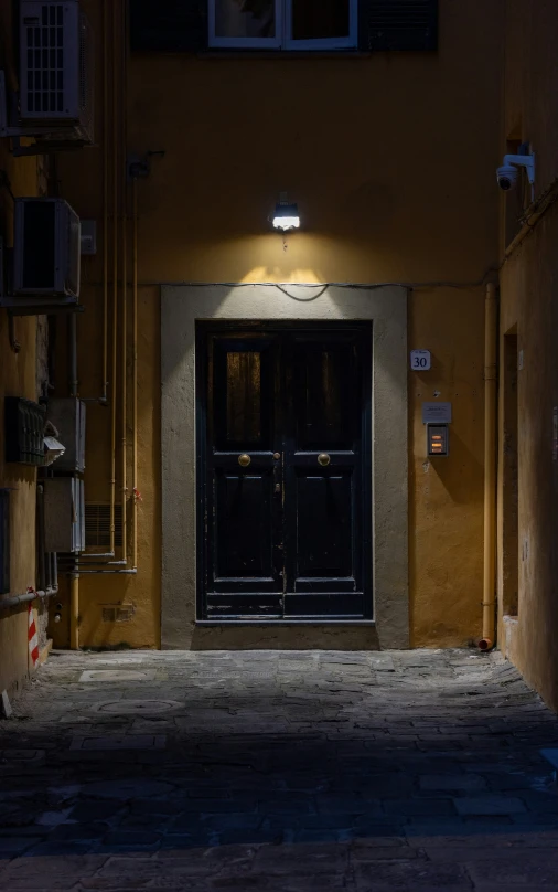 a black door is seen at night on an alleyway
