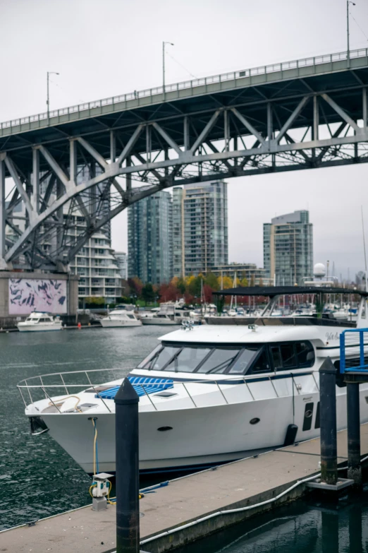 a white boat parked near a dock underneath a bridge