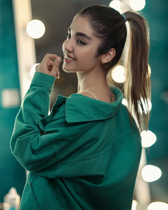 girl with a ponytail standing in a green sweatshirt looking at the camera