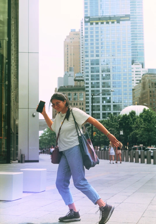 a woman walking down the street, taking pictures with her cell phone