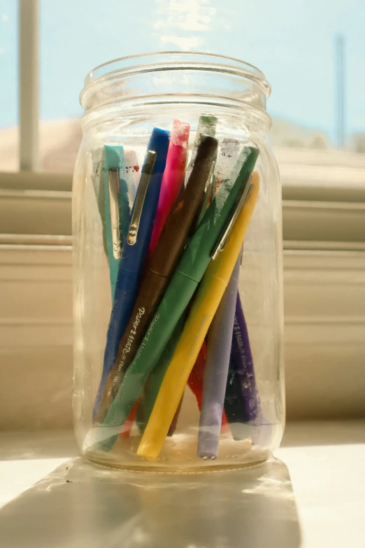 a glass jar full of assorted colored pencils
