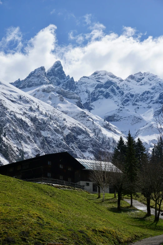 the mountains are covered in snow and green grass