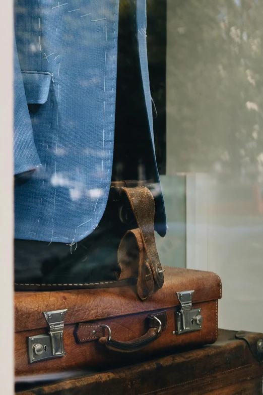 the back side of an old suitcase with blue jacket on top