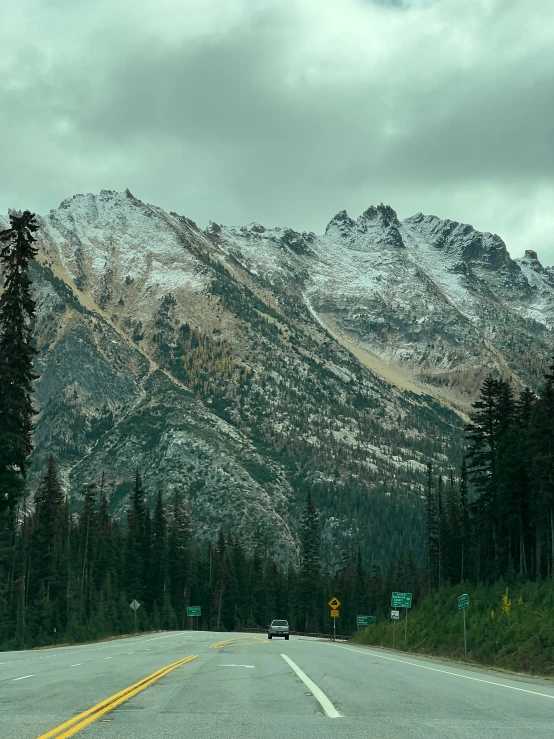 a highway with trees, mountains and cars
