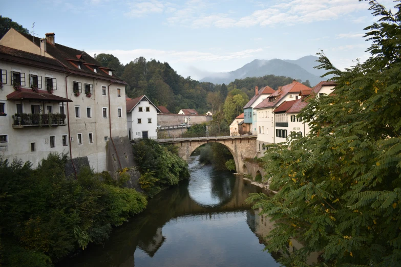 the small river runs underneath the bridge that carries it