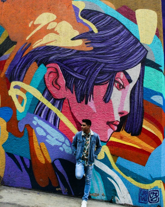 a man stands in front of a large colorful graffiti wall