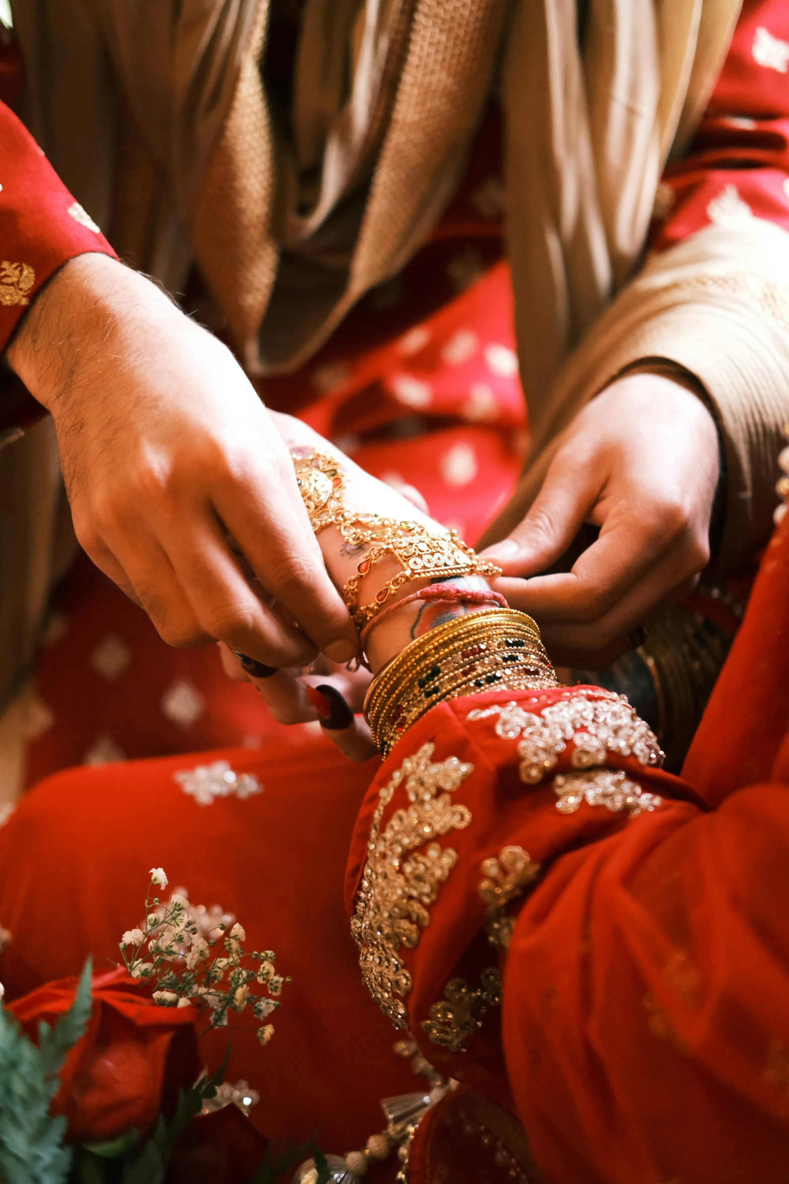 a person in red is placing a celet on another woman's wrist