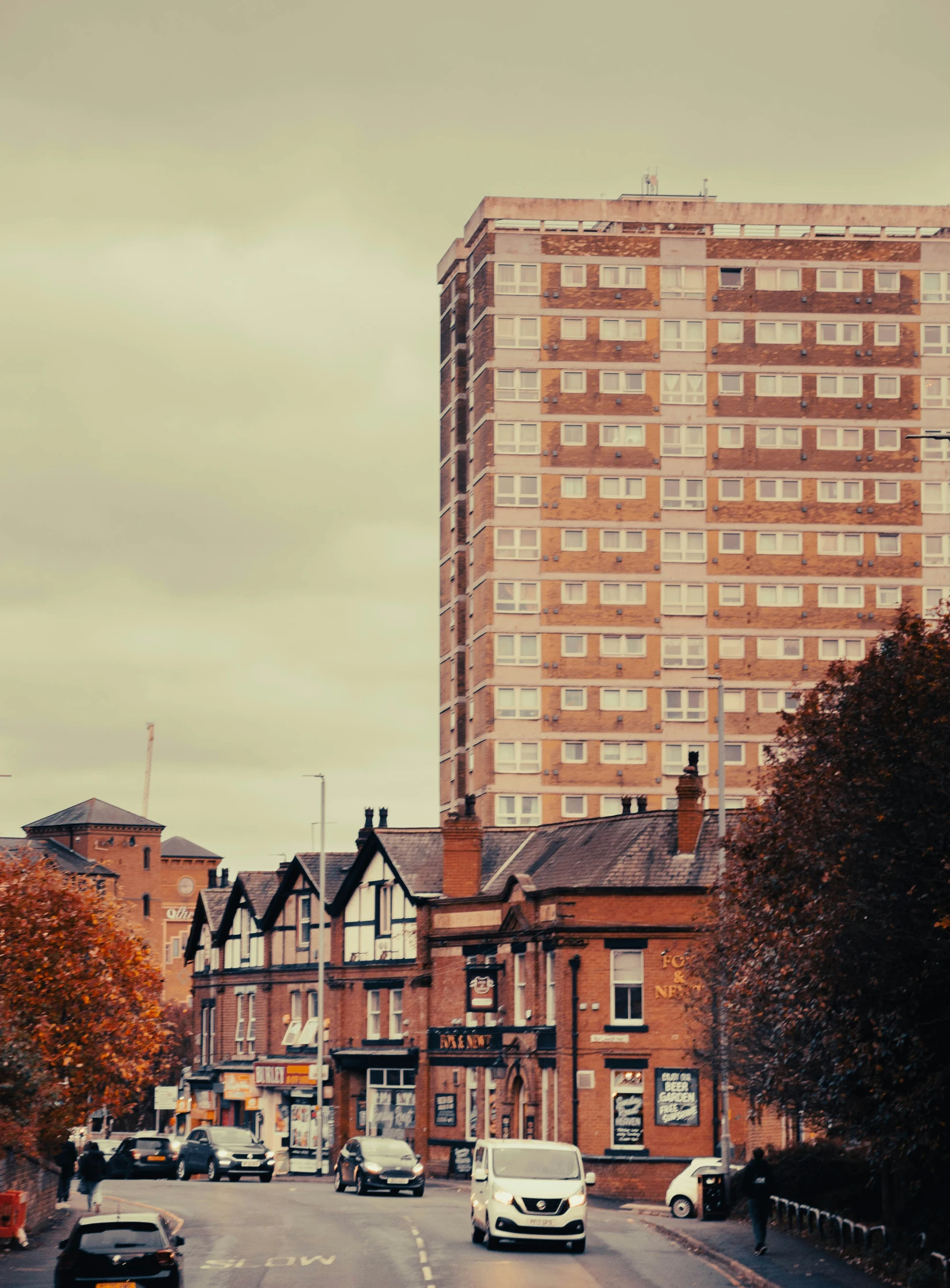 cars are parked along the road in front of tall buildings