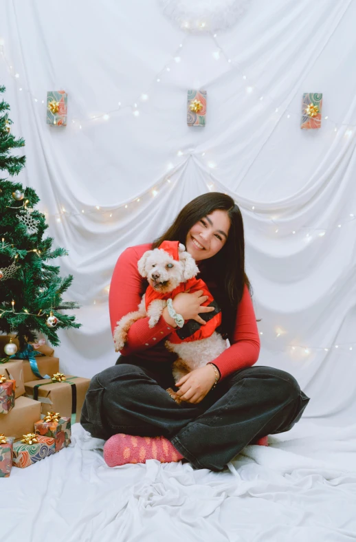 a girl in a red shirt and her dog by a christmas tree