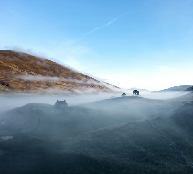 mist covering a valley with mountains in the background