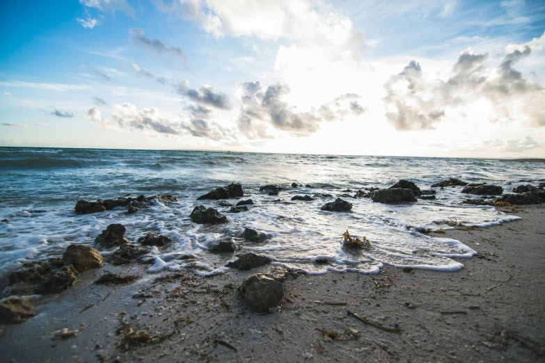 a beautiful day at the beach with waves hitting a sandy beach and crashing into the water