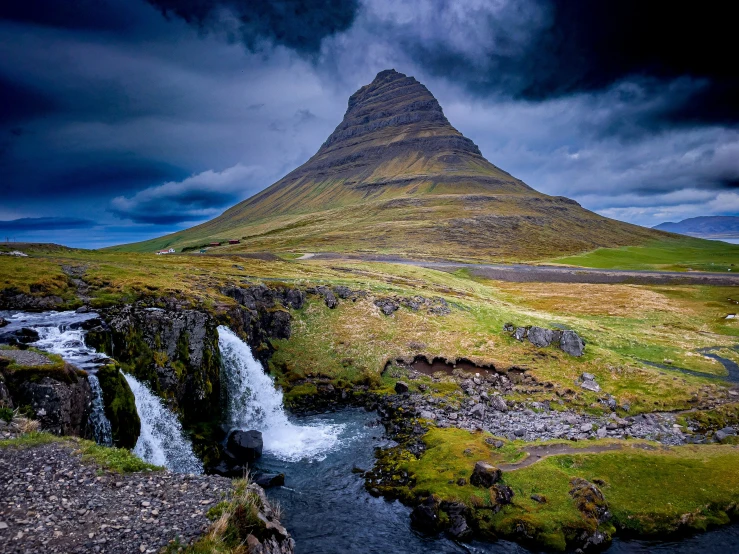 mountain towering over small waterfall at dark