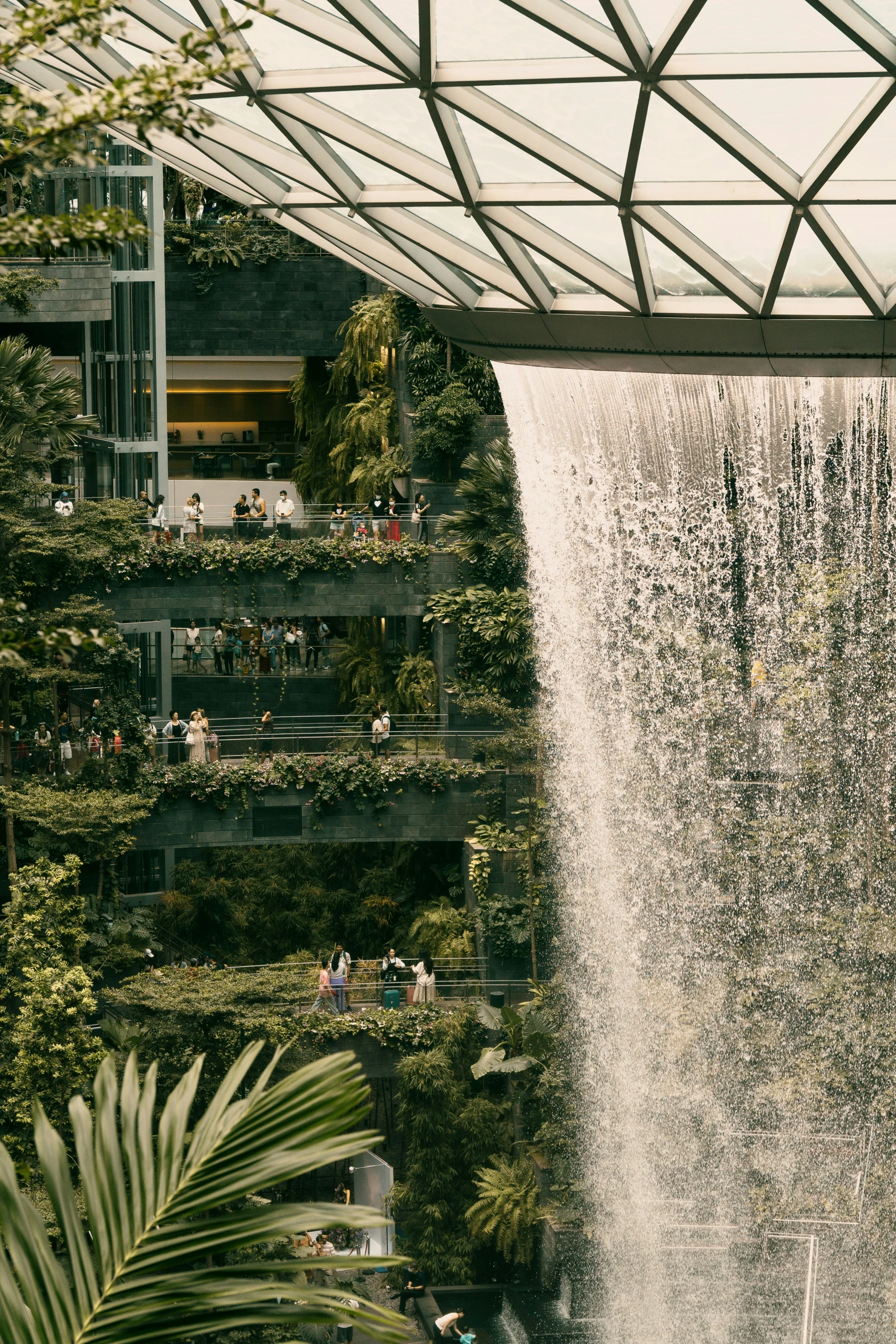 a tall waterfall in the center of a green house