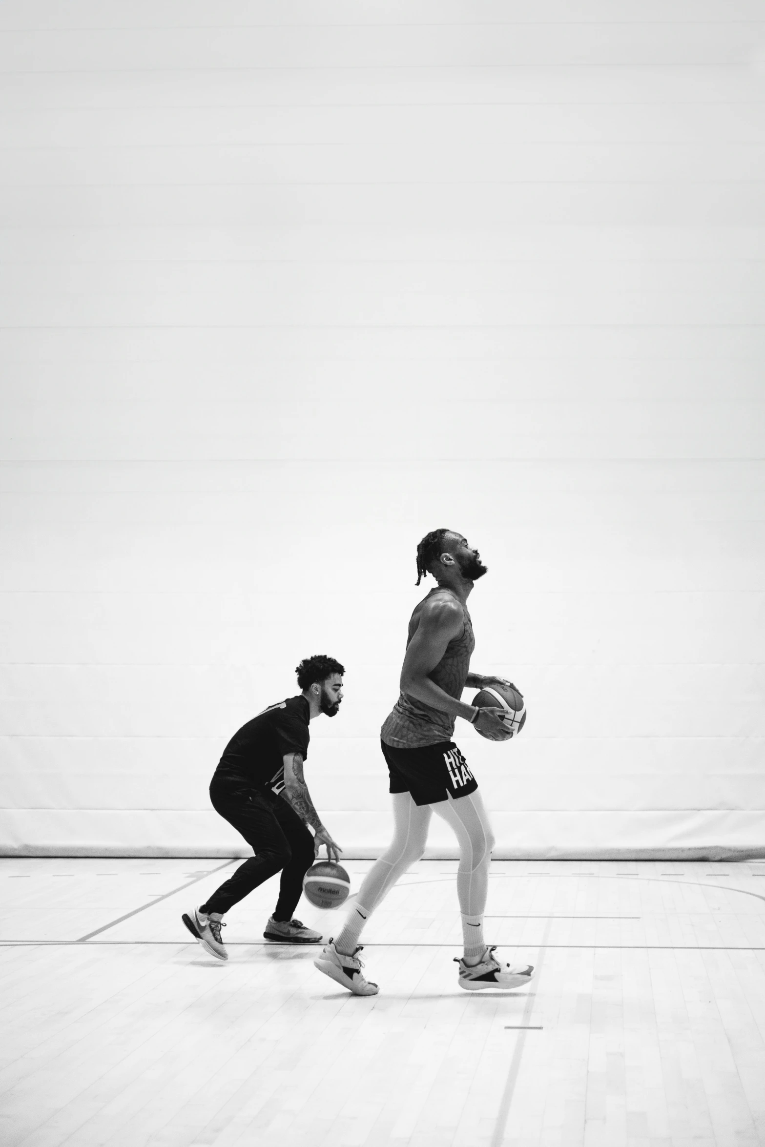 two people walking down the sidewalk holding tennis balls