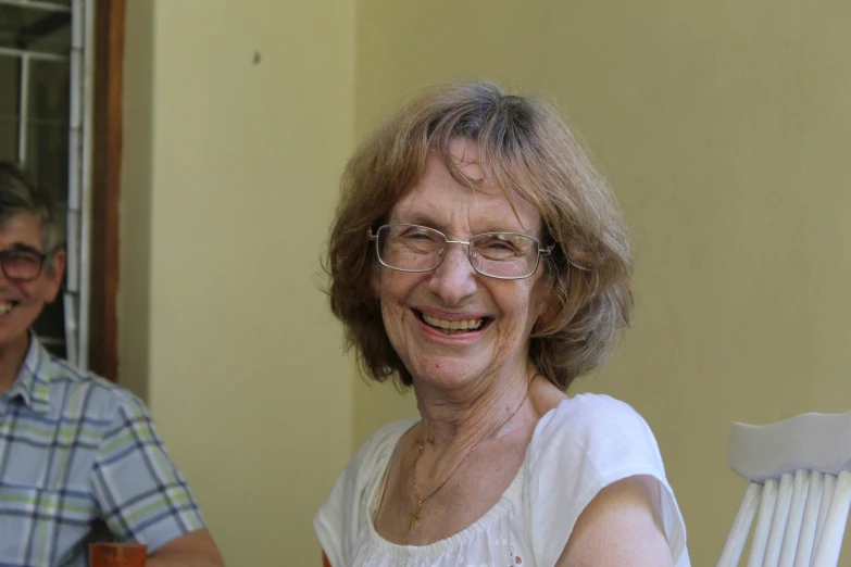 an elderly woman smiling with her companion in background