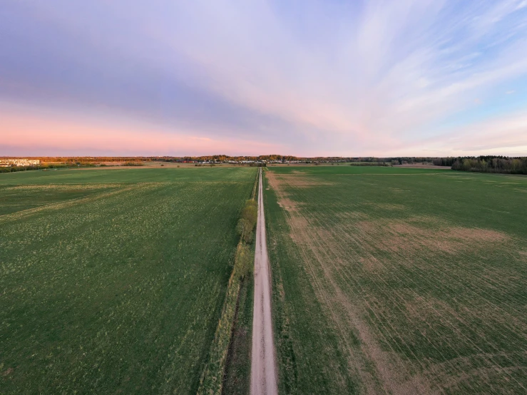 an open field with grass and a paved road leading to it