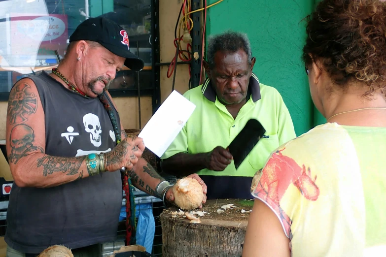 a man in a green shirt is examining an onion with other men standing around him