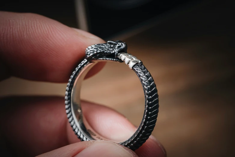 a person is holding a silver ring with diamonds