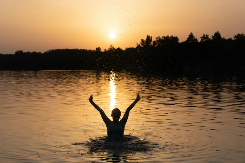 a person is swimming in the water at sunset