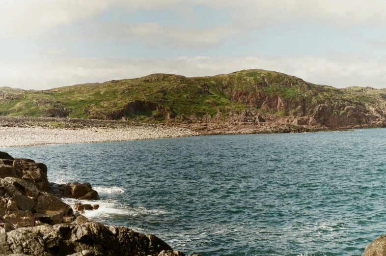 a bunch of rock in the water near a hill